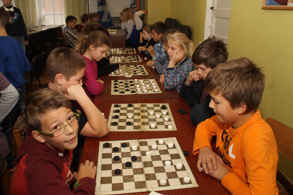 Griķu (no kreisās) un Mežgaļu pamatskolas vienības tiekas pie dambretes galdiņa. 
Autors: Uldis Varnevičs