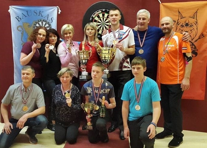 Oskars Kovaļevskis (pirmajā rindā no kreisās), Lonija Stare, Rihards Slišāns, Areta Kovaļevska (otrajā rindā otrā no kreisās) un Guntars Stipins (otrajā rindā no labās) – godalgoto vietu ieguvēji Latvijas čempionātā šautriņmešanā. 
Autors: no latviadarts.com