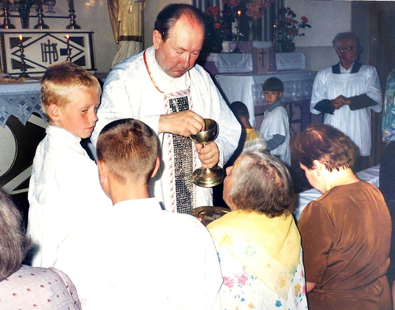 Priesteris Pēteris Skredeļs pasniedz Vissvētāko sakramentu Tomam Bužeriņam (no kreisās), viņa brālēnam Ainim un vecmāmiņai Johannai Jaungailei. Tagad Tomam ir 31 gads.
Autors:  no albuma. 