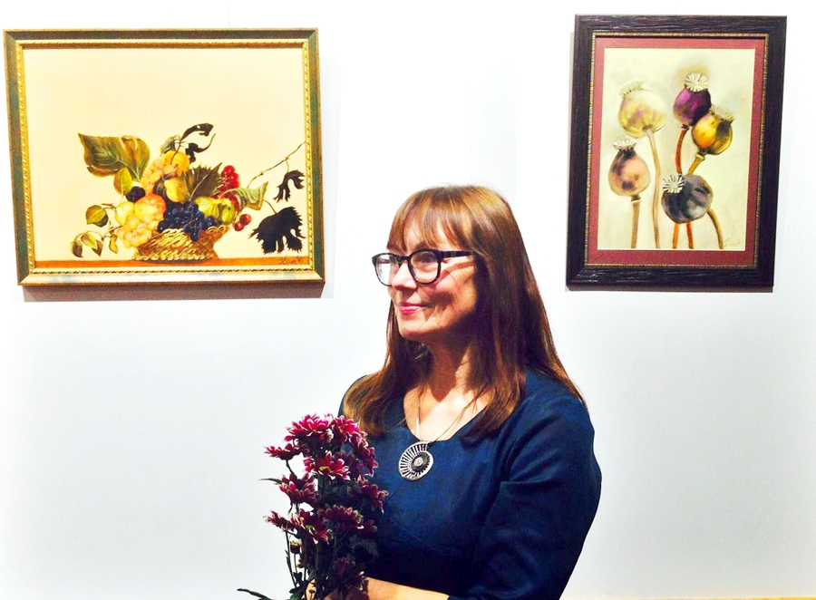 Ina Krūmiņa personālizstādes atklāšanā. Fonā – viņas gleznotā Karavadžo klusās dabas kopija.
Autors: no biedrības «Meistars Gothards» albuma