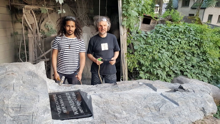 Pieminekli veido mākslinieks Tālivaldis Muzikants (no labās) kopā ar dēlu Emīlu Kristiānu, kurš mācās Latvijas  Mākslas akadēmijā  par  tēlnieku un palīdzēja tēvam pieminekļa tapšanā.  Akmens augstums 3,30 m un platums 1,55 m.
Autors: No draudzes arhīva.