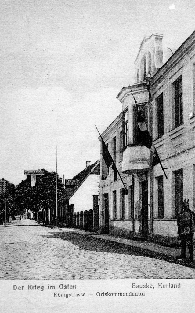 Friča Grīšļa nams tagadējā Plūdoņa ielā 14 Pirmā pasaules kara laikā, kur tolaik atradās vācu komandantūra, bet 1918. gada nogalē bija iecerēts izvietot vidusskolu. 
Pastkarte no Bauskas muzeja krājuma.