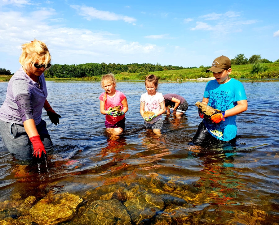 Mežotniece Ramona Zoliņa (no kreisās) pati ir azartiska makšķerniece, un, viņasprāt, esot tikai pašsaprotami uzlabot savas copes vietas. Talciniekiem īpaši norādījumi zivju nārsta veidošanai netika doti, bet bija ļauts improvizēt. Ramona uzņēmās koordinēt darbus lielākajiem palīgiem – meitai Madarai (blakus) un kaimiņu bērniem Luīzei un Dominikam Ziboliem.
