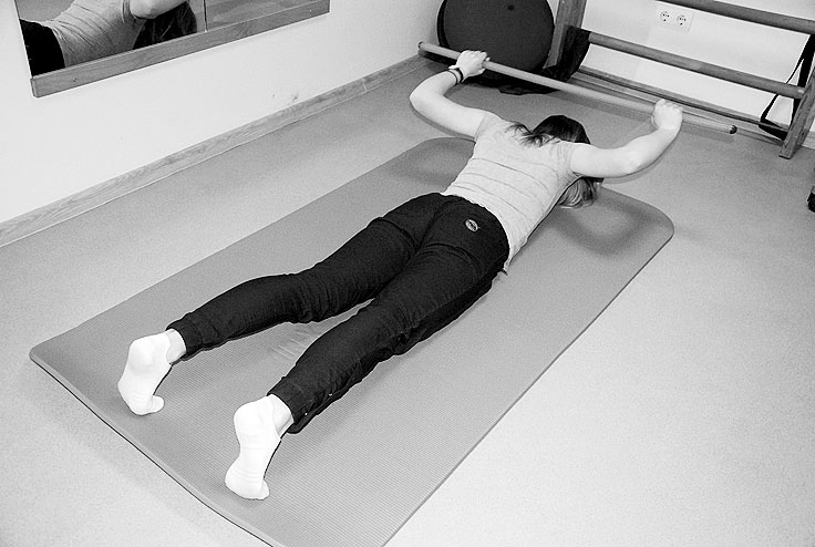 Vingrinājums starplāpstiņu muskulatūras stiprināšanai un krūšu muskulatūras pastiepšanai. Lai galva nebūtu jāgriež pa labi vai pa kreisi, zem pieres paliek spilventiņu. Paņem nūju vai tai līdzīgu priekšmetu, piemēram, slotu. Paceļ aiz galvas, nolaiž uz grīdas sev priekšā.