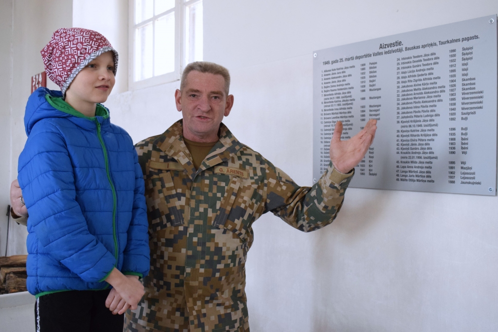 Dažādu paaudžu vallieši – Guntis Ārents un Kristers Ruģelis, Diānas un Imanta Ruģeļu mazdēls, – apskata piemiņas plāksni. Zīmīgi, ka Kristeram tieši 25. martā ir dzimšanas diena, viņam paliek 11 gadu.
Autors: Žanna Zālīte