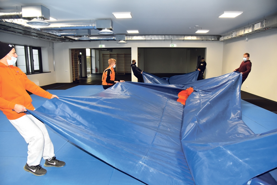 Brīvās cīņas pārstāvji jaunās sporta halles zālē uzvelk lielo cīņas paklāju.
Autors: Uldis Varnevičs