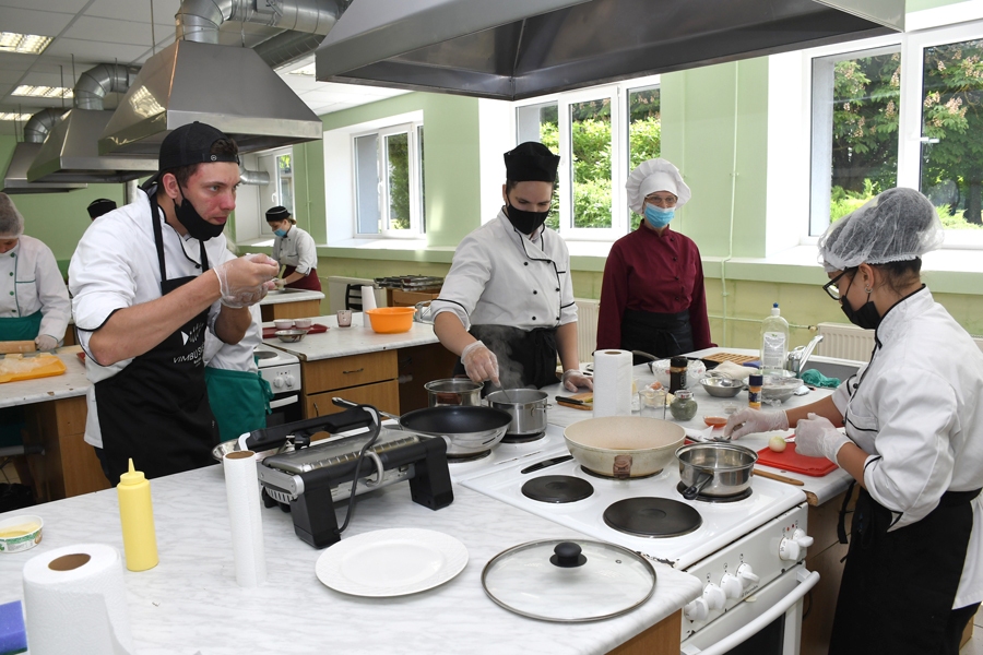 Ēdināšanas specialitātes studenti Emīls Šmits (no kreisās), Beāte Ilgavīze un Oksana Paegle (no labās) gatavo maltīti, ko piedāvās 
eksaminācijas komisijai. Procesu no malas vēro ēdienu gatavošanas pasniedzēja Egita Rancāne.
Autors: Ivars Bogdanovs