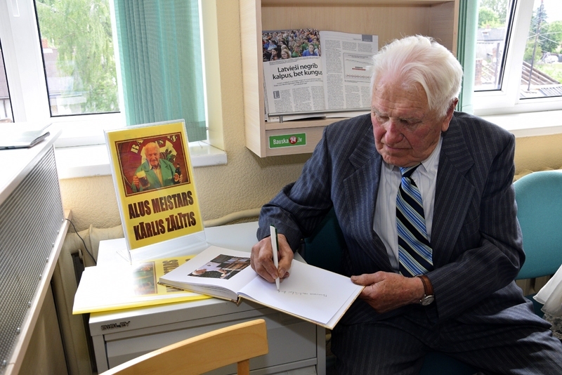 Kārlis Zālītis 90.jubilejas vasarā. Bauskas Centrālās bibliotēkas interneta lasītavā 2016. gada 9. jūnijā interesenti pulcējās grāmatas par Kārli Zālīti «Sirds pareizajā pusē» atvēršanas svētkos. Attēlā – Meistars K.Zālītis grāmatā ieraksta vēlējumus un dala interesentiem autogrāfus.
Autors: no «Bauskas Dzīves» arhīva.