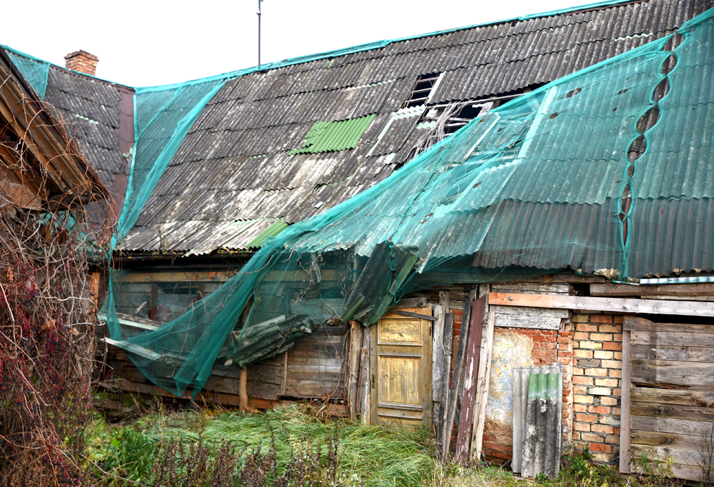 Gar Kalna ielu celtā ēkas austrumu spārna rietumu (pagalma) puses fragments. Redzams, ka 2023. gadā nostiprinātās ēkas jumta segums daļēji norauts šīs vasaras vētrās. 
Autors: Foto – D. Bruģis