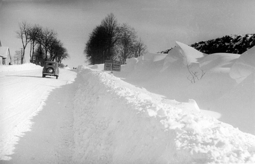 No sniega attīrīta šoseja Rīga–Pleskava pirms krustojuma ar autoceļu Cēsis–Madona, bet tālumā vēl strādā ceļu uzturēšanas darbinieki ar lāpstām. 1946. gada ziema. Foto no Latvijas Ceļu muzeja.